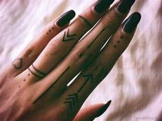 a woman's hand with two small tattoos on her left wrist and the middle finger