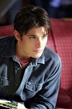 a young man sitting on a red couch looking at the camera