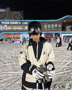 a person standing in the snow with skis and goggles on, holding something