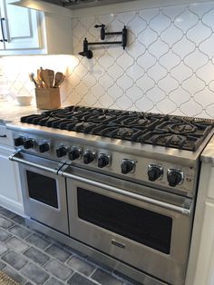 a stove top oven sitting inside of a kitchen next to a countertop with utensils on it