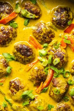 meatballs and vegetables in a yellow sauce with green onions, carrots and peppers