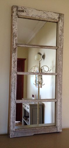 an old window frame with a mirror on the wall and a light fixture in front of it