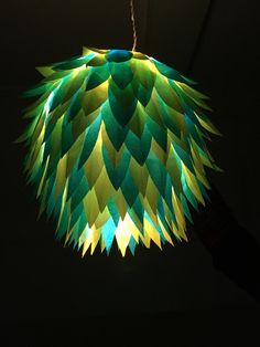 a green and yellow paper light hanging from a ceiling