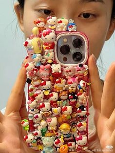 a woman holding up her cell phone case with hello kitty decorations on the front and sides