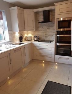 a kitchen with white cabinets and lights on the counter tops, along with an oven