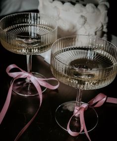 two wine glasses with pink ribbon and bow on the table next to eachother