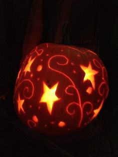 a pumpkin carved to look like stars and swirls with the letter s on it