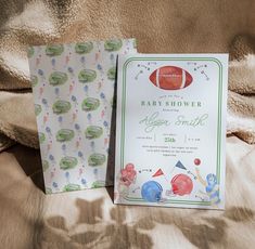 two baby shower items sitting on top of a bed next to each other, one with an american football design