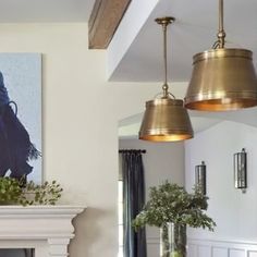 a living room filled with furniture and a fire place under two hanging lights next to a fireplace