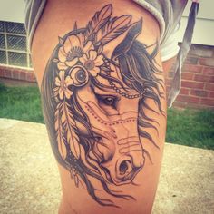 a woman's leg with a horse tattoo on it and flowers in her hair