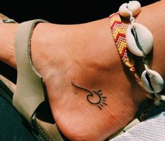 a woman's foot with a small tattoo on the side of her body and seashells attached to it