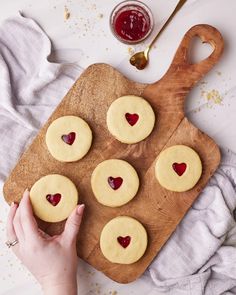 a wooden cutting board topped with heart shaped cookies