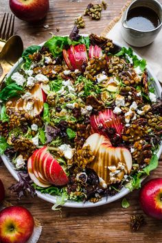 an apple and walnut salad on a white plate with two silver spoons next to it