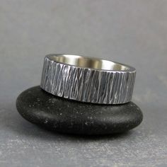 a silver ring sitting on top of a black rock