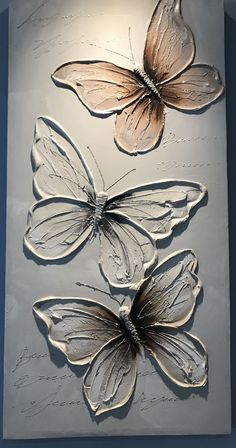 three metal butterflies mounted to the side of a wall