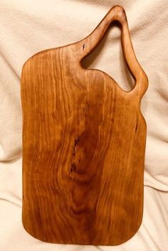 a wooden cutting board sitting on top of a white cloth covered tablecloth with a wood handle