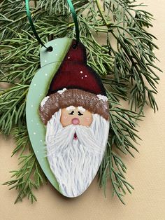 an ornament with a santa clause on it hanging from a christmas tree branch