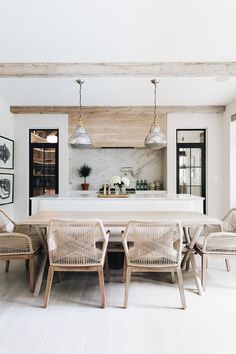 the dining room table is surrounded by wicker chairs and white marble countertops, with an island in the middle