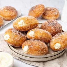 some sugared doughnuts are on a plate next to other pastries and milk