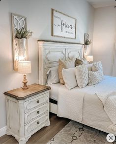 a white bed sitting in a bedroom next to a dresser and lamp on top of a wooden floor