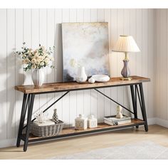 a wooden table with two vases on it and a painting in the corner next to it