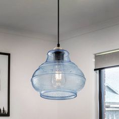 a blue glass light hanging from a ceiling in a room with pictures on the wall