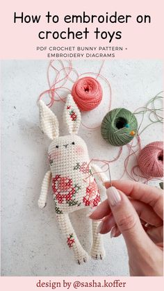 a hand holding a needle next to some crochet toys