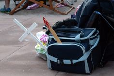 an open bag sitting on the ground next to some chairs and other things in it