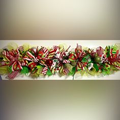 a green and red christmas bow with candy canes on it's side,