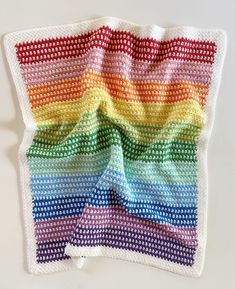 a multicolored crocheted blanket on a white surface