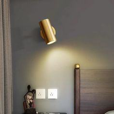 a bed room with a neatly made bed and a lamp on the wall above it