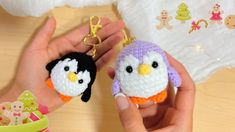 two small crocheted penguin keychains are being held by someone's hand