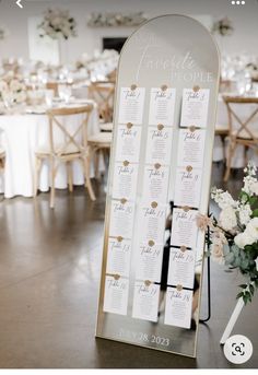 the seating chart is on display in front of tables with white flowers and greenery