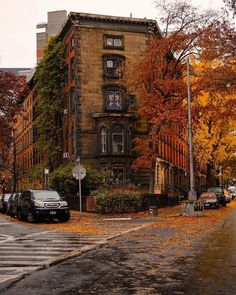 an old brick building with lots of windows on the corner in front of some parked cars