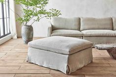 a living room with a couch, ottoman and coffee table in front of a window