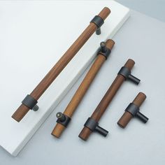 four pieces of wood with black handles on a white surface, including one handle and the other