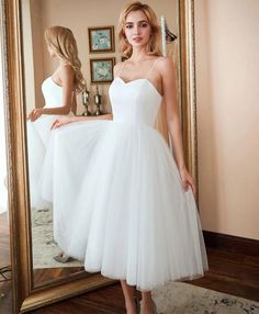 a woman standing in front of a mirror wearing a white dress