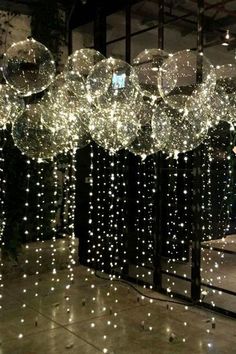 some lights hanging from the ceiling in front of a window with balls attached to it