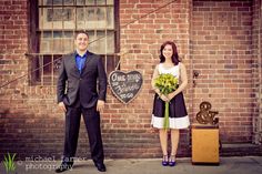 a man and woman standing in front of a brick building