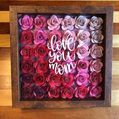 a shadow box filled with pink and red paper flowers that say love you mom on it