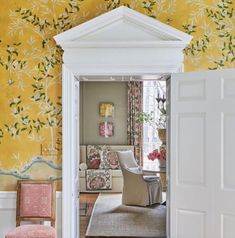 an open door leading to a living room with yellow walls and floral wallpaper on the walls