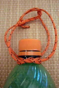 a green bottle with an orange strap around it's neck sitting on a table