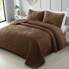 a bed in a room with a brown comforter and pillows on top of it