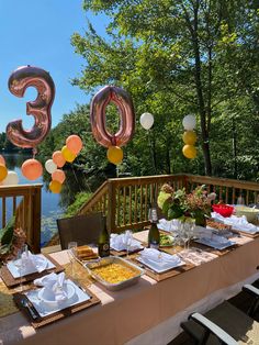 the table is set with balloons, plates and utensils for an outdoor celebration