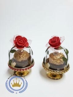 there are two small bells with roses in them on top of each other, one is gold and the other has a red rose