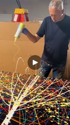 an older man is painting sprinkles on a cardboard box