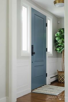 a blue door in a white room with wood floors and a rug on the floor