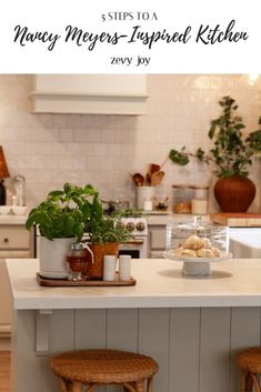 a kitchen island with two stools next to it and plants in pots on top