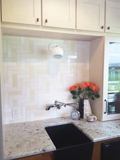 a kitchen with white cabinets and marble counter tops, black sink in the corner next to an open microwave