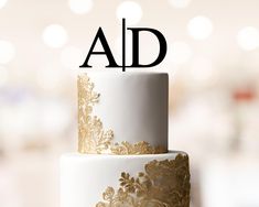 a white and gold wedding cake with the letter ad on top